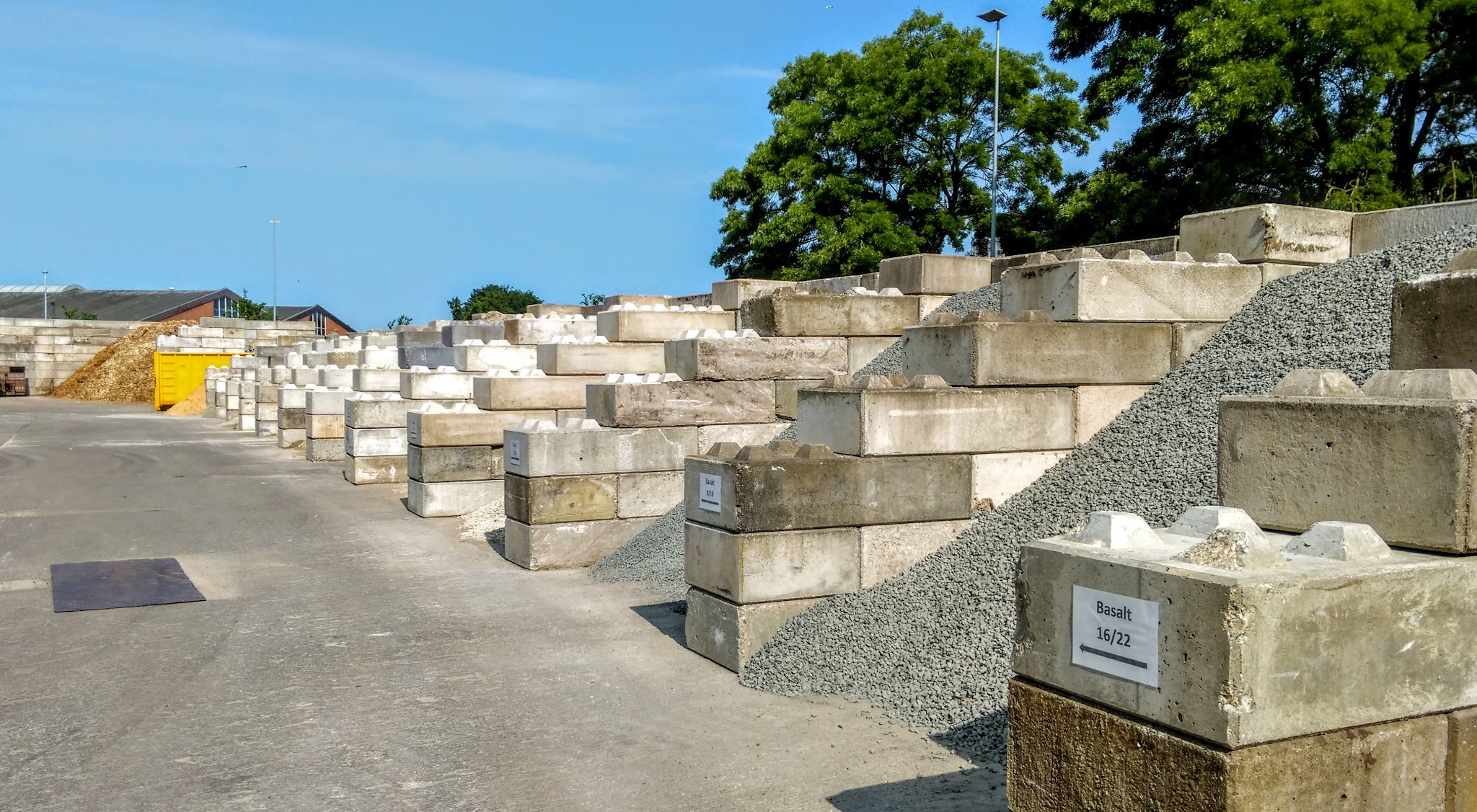 Vakken van betonblokken met grind en split op de werf, met een bord Basalt 16/22 vooraan